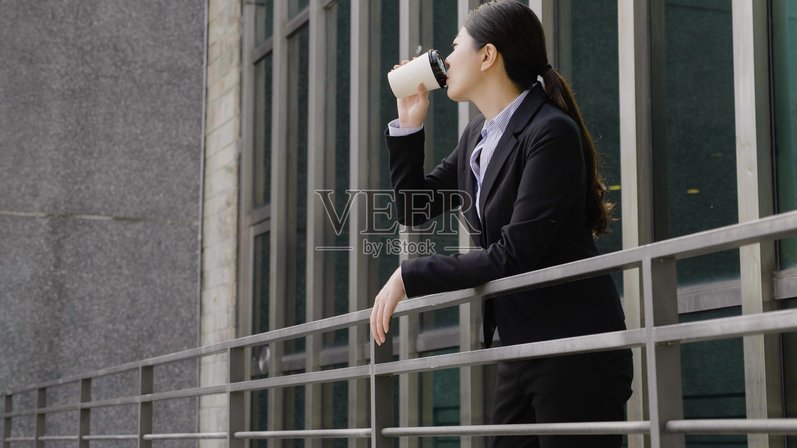 女商人靠在阳台上喝咖啡照片摄影图片