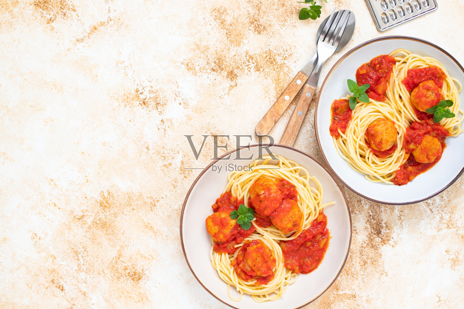 意大利细面条意大利细面条加肉丸和番茄酱和牛至叶放在两个碗里，放在一个轻大理石桌子上。俯视图，复制空间照片摄影图片