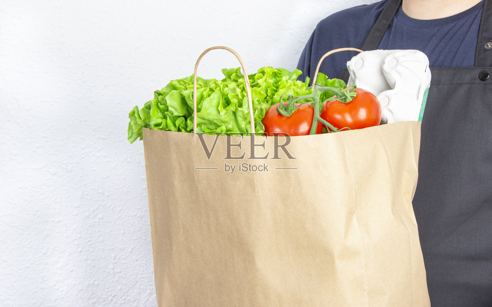 男人拿着一个装有生菜、番茄和鸡蛋的纸袋照片摄影图片