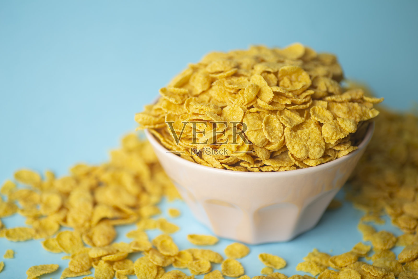 早餐麦片(玉米片)，放在蓝色背景上的粉色碗里。水族艺术创意食物概念照片摄影图片