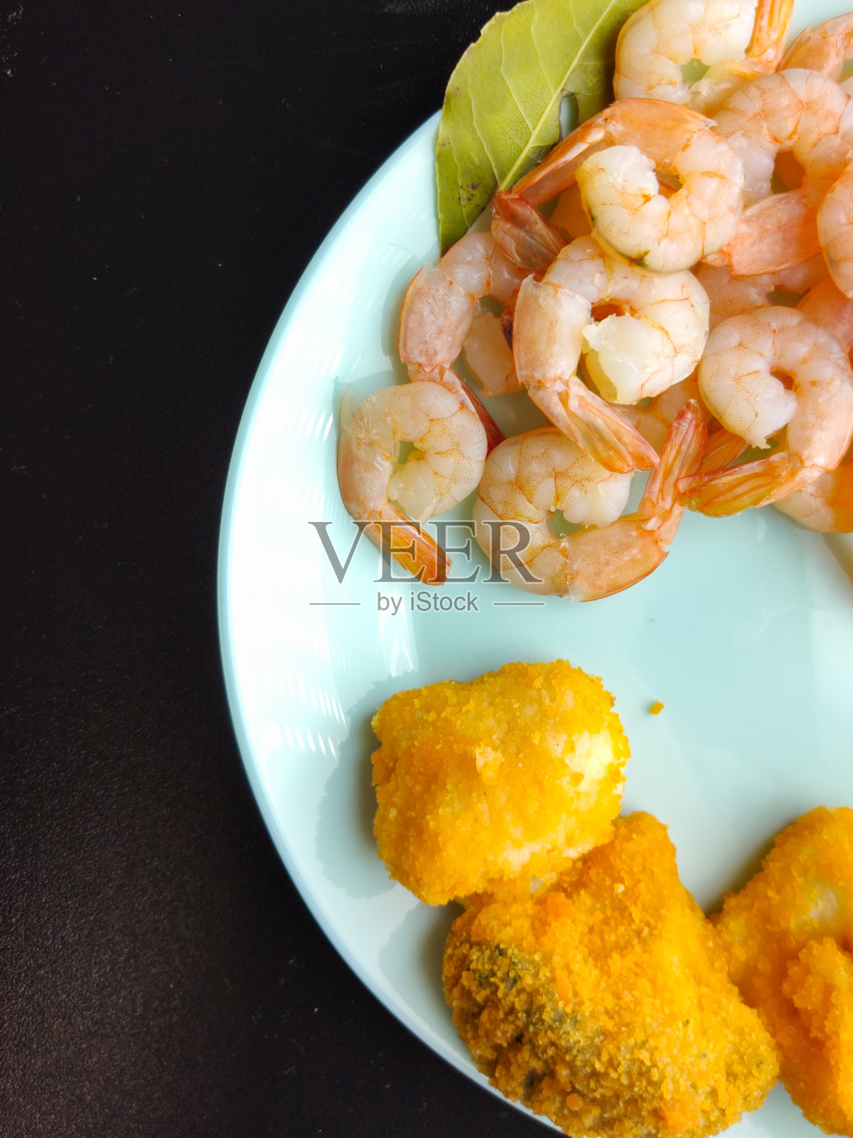 鲜虾、柠檬和花椰菜放在蓝色盘子里特写。西兰花覆有面包屑的照片摄影图片