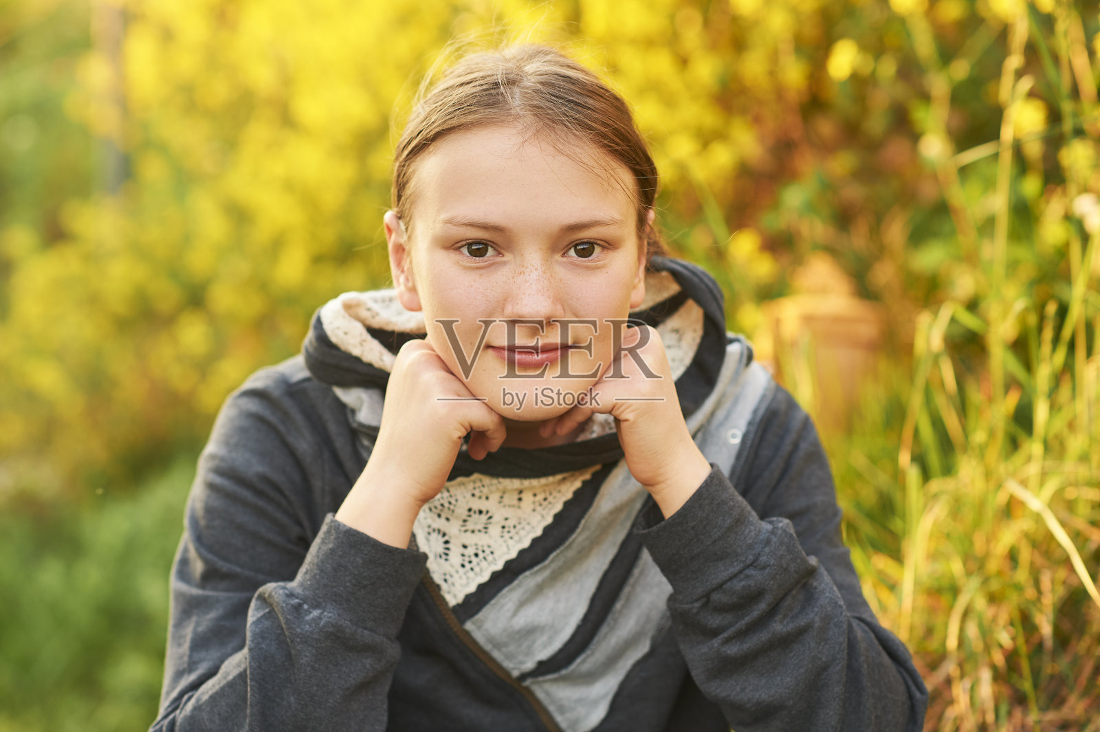 户外近距离拍摄的年轻女孩倚着头，在公园里享受温暖的一天照片摄影图片