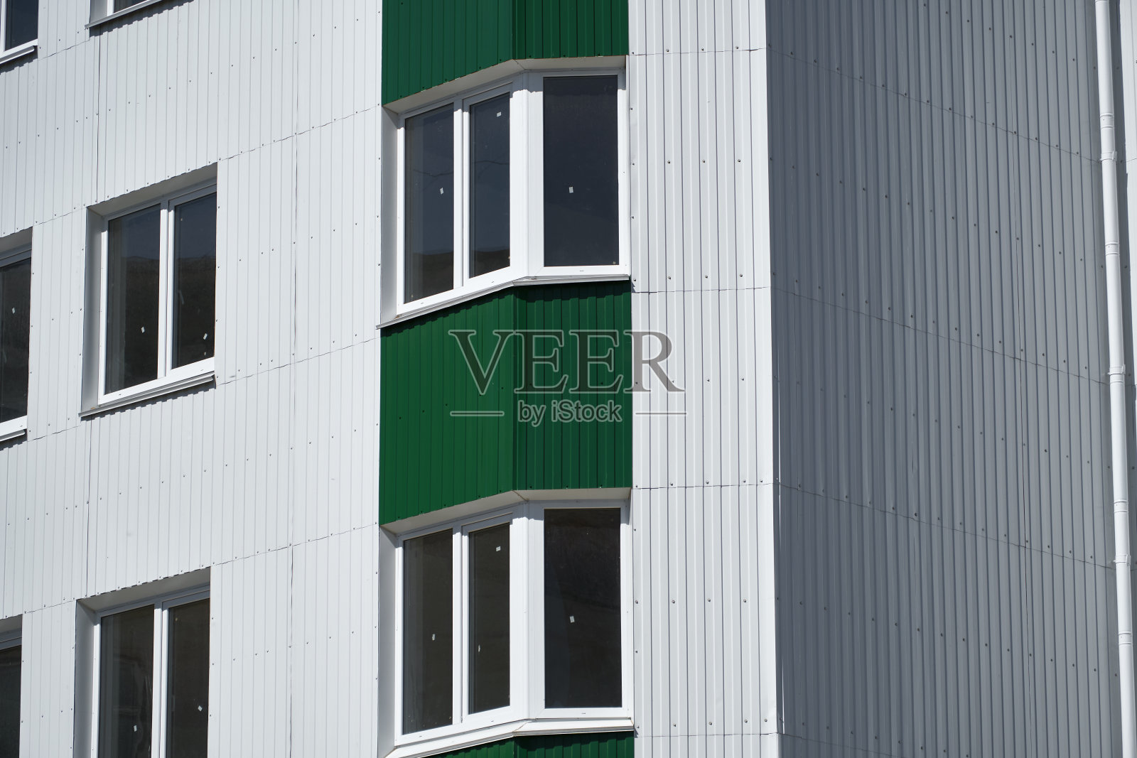 带白色和绿色金属壁板的多层建筑外墙照片摄影图片