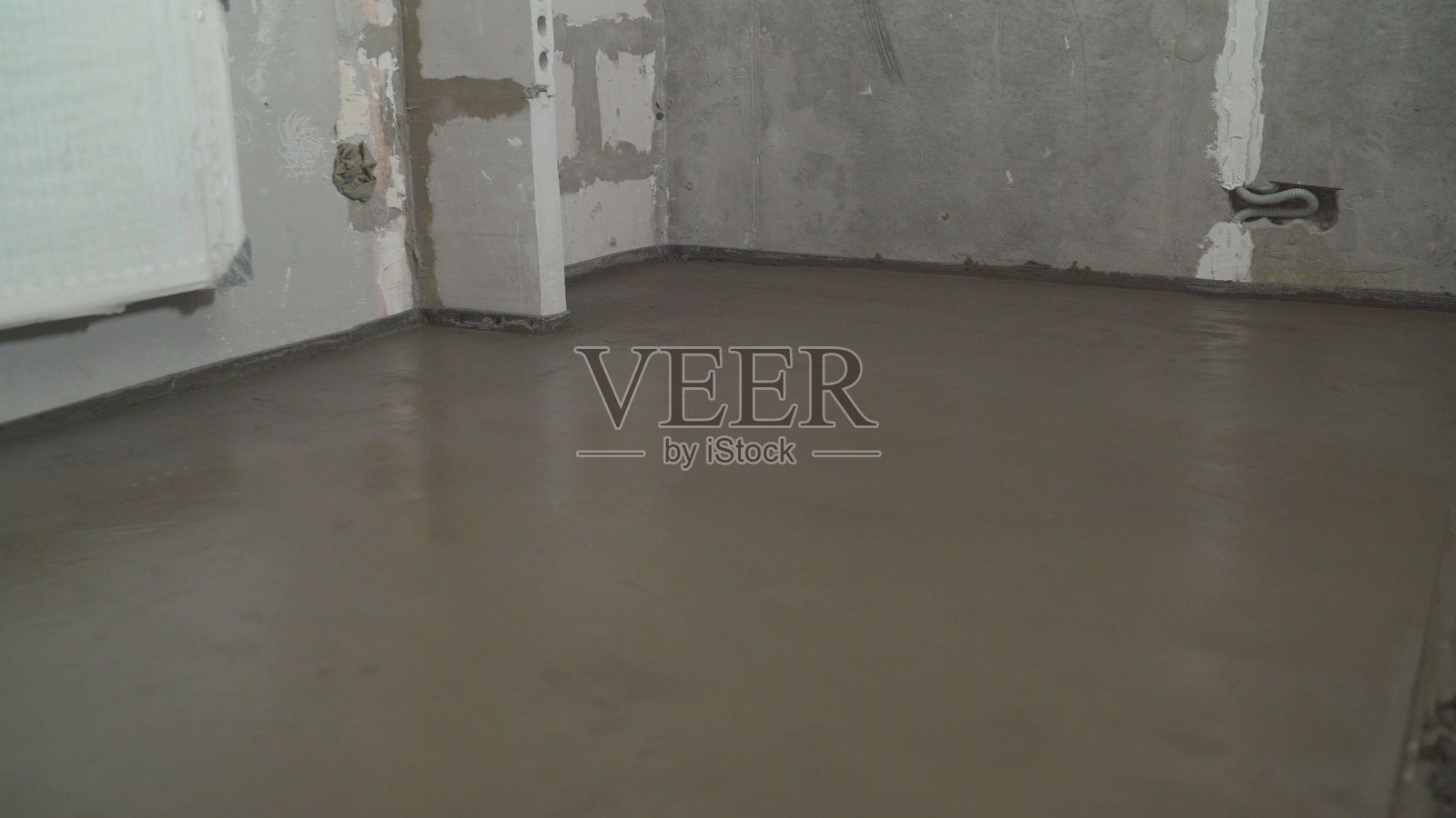 工人用沉石把地板弄平。建筑技术人员正在把混凝土地板弄平。照片摄影图片