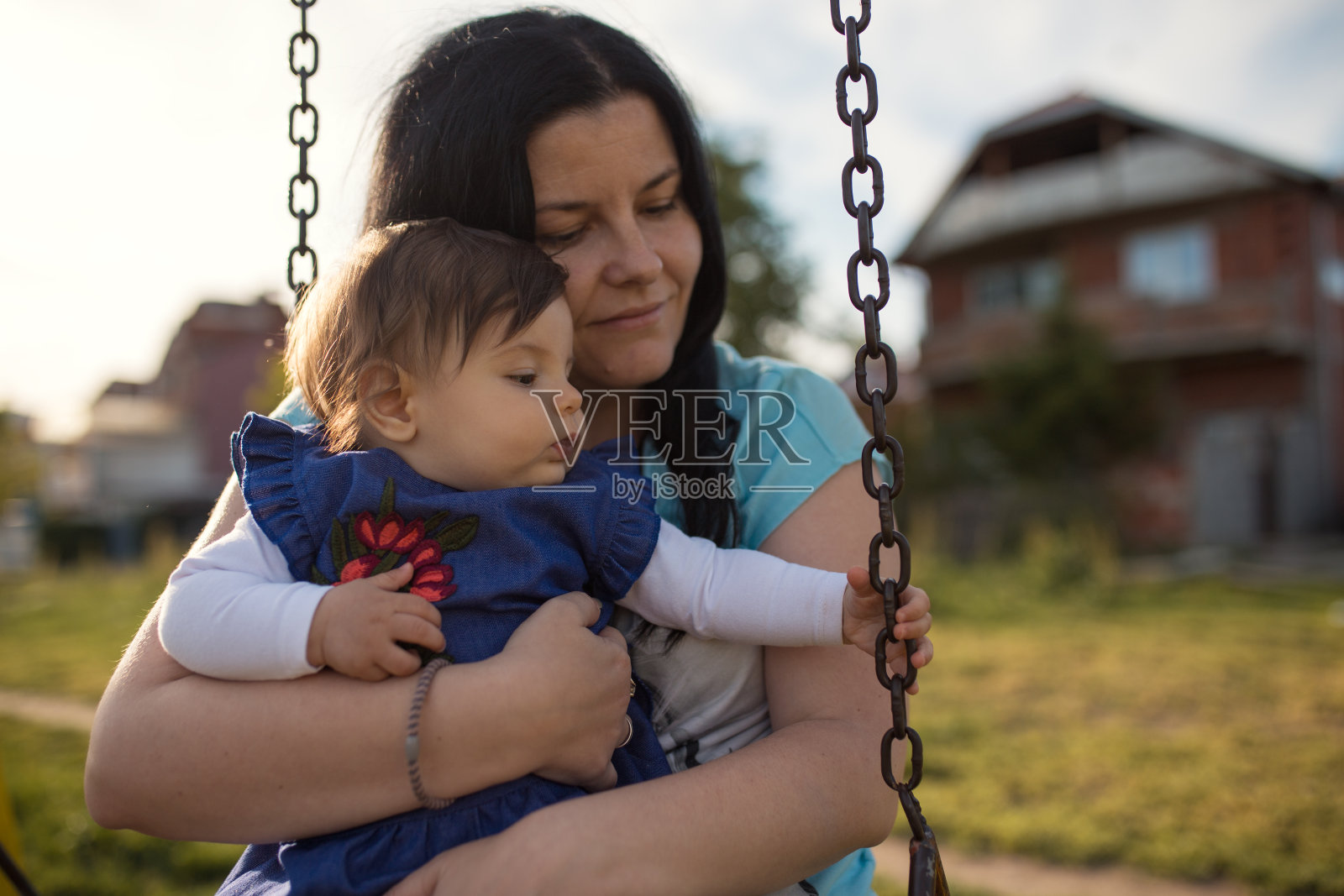 妈妈抱着她的孩子在操场上照片摄影图片