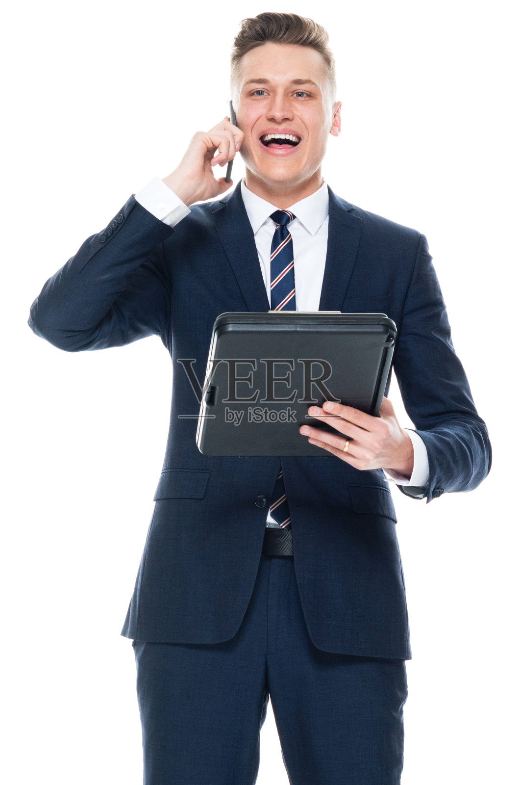 白人年轻男性商人穿着商务服站在白色背景前，手持文件，使用手机照片摄影图片