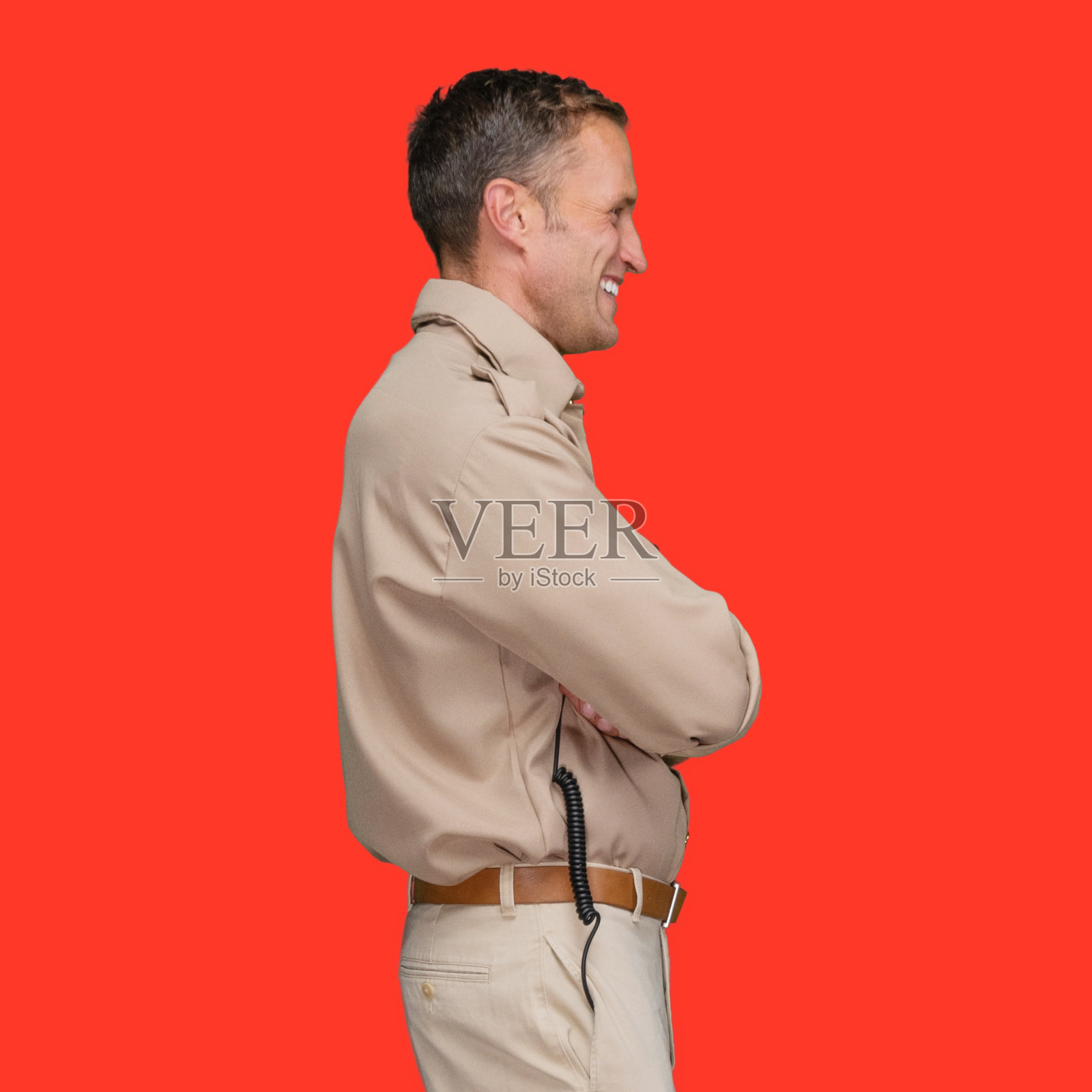 白人男性警察站在有色背景前佩戴警徽照片摄影图片