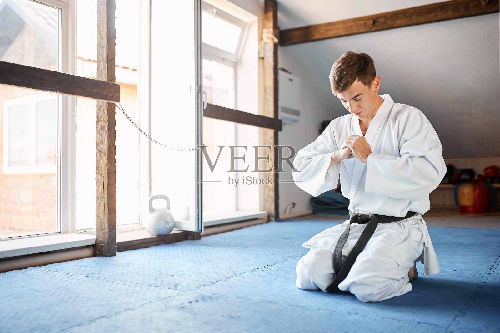 在武术馆里，穿着和服的空手道男跪在地板上照片摄影图片