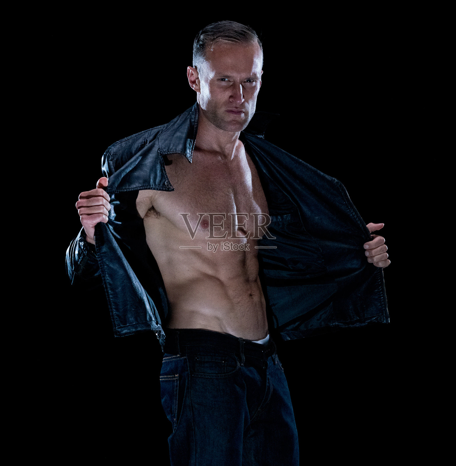 白人男性穿着皮夹克站在黑色背景前照片摄影图片