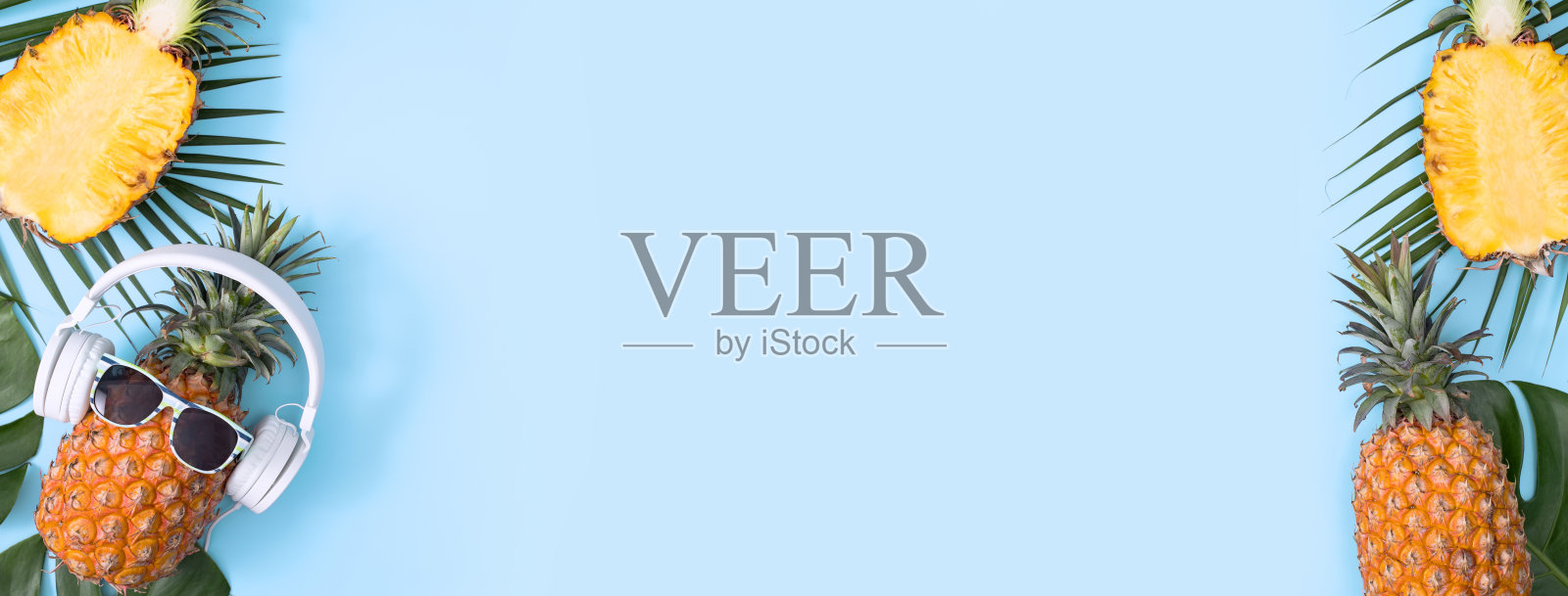 有趣的菠萝戴着白色耳机，概念听音乐，孤立在彩色背景与热带棕榈叶照片摄影图片