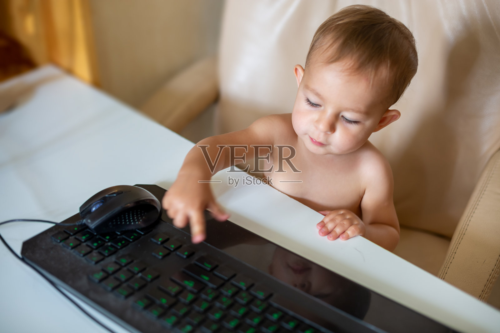 婴儿坐在办公椅上敲击键盘照片摄影图片