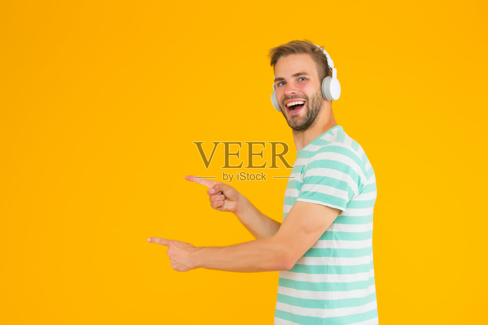 听英雄音乐感觉更积极主动和鼓舞。男人指着拷贝空间。完美的声音概念。快乐的人听音乐耳机。无线耳机。器乐照片摄影图片