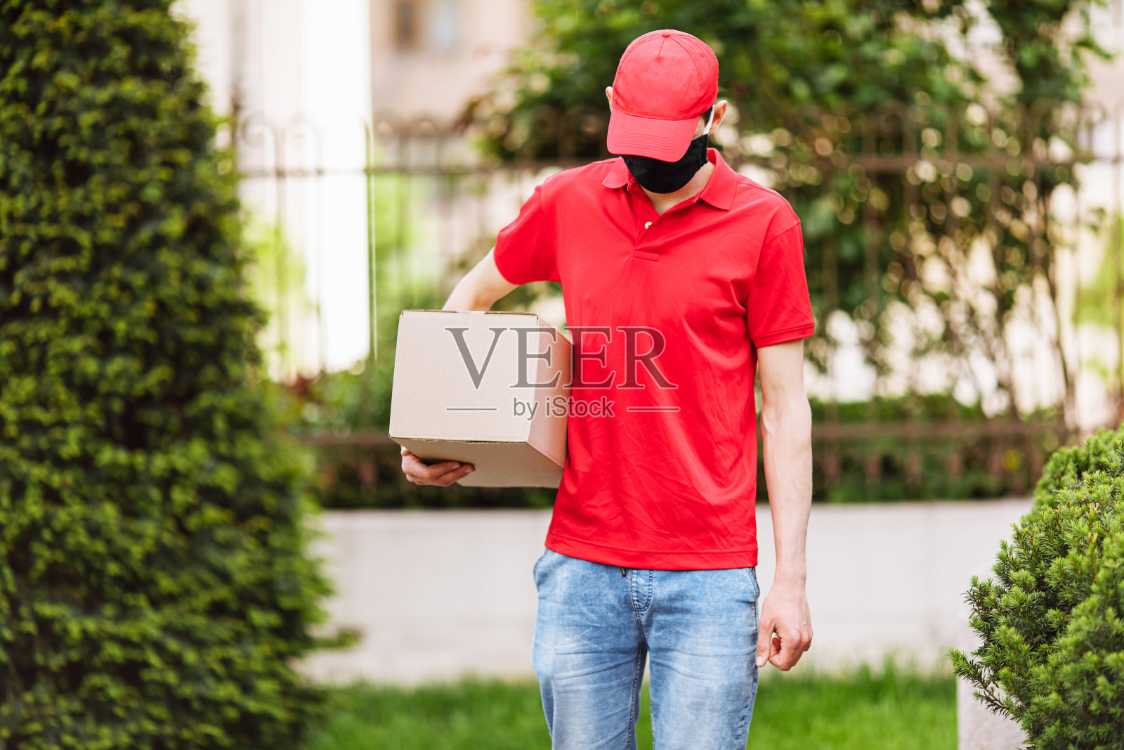 快递员拿着装着医用防护口罩的纸盒。快速免费运输。照片摄影图片