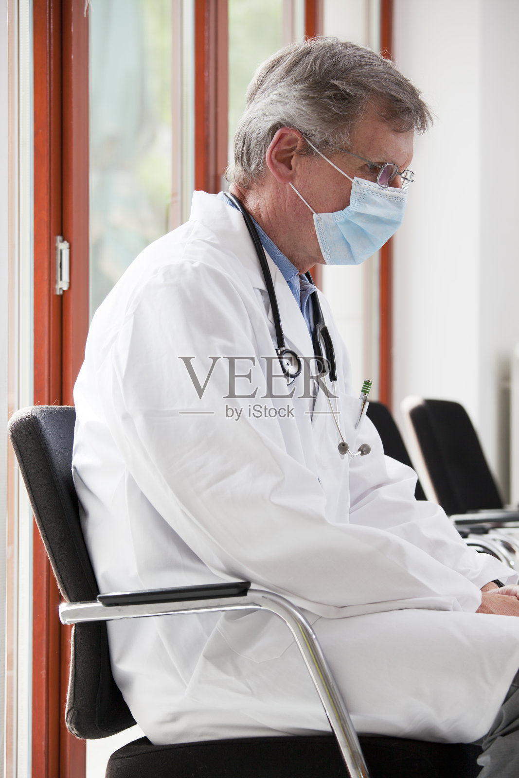 疲惫不堪的医生坐在医院或诊所明亮的候诊室里，专注于脸部照片摄影图片