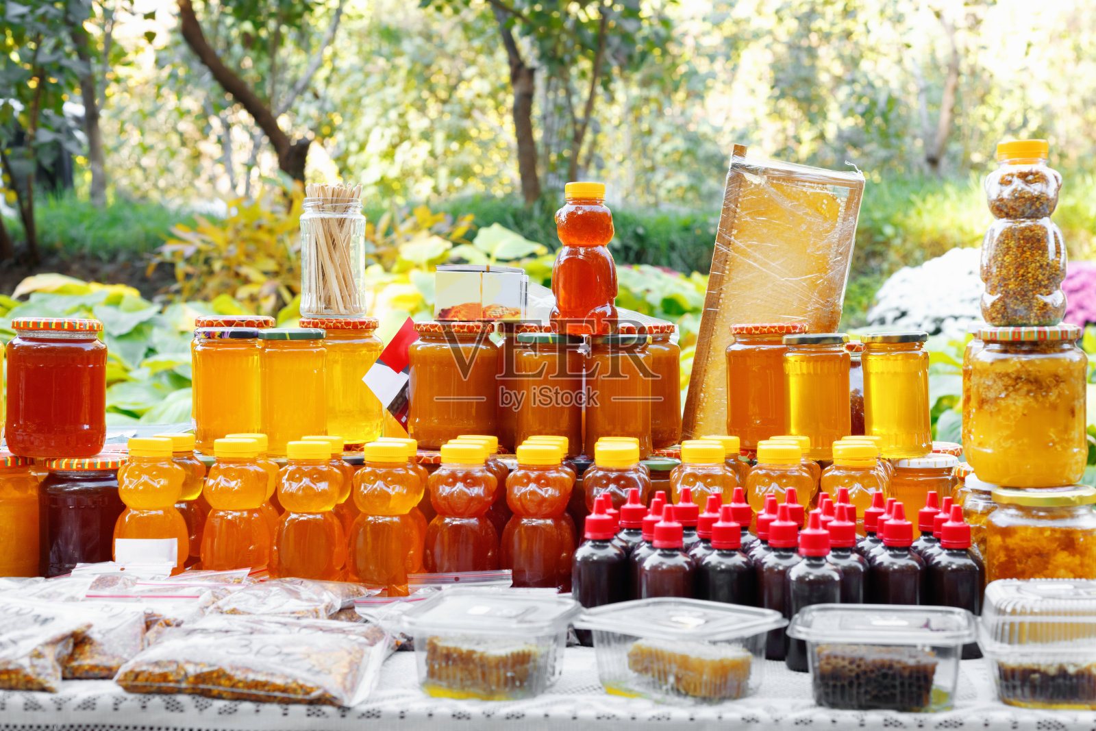 市场摊位上各种各样的蜂蜜罐。户外集市售卖天然蜂蜜。照片摄影图片