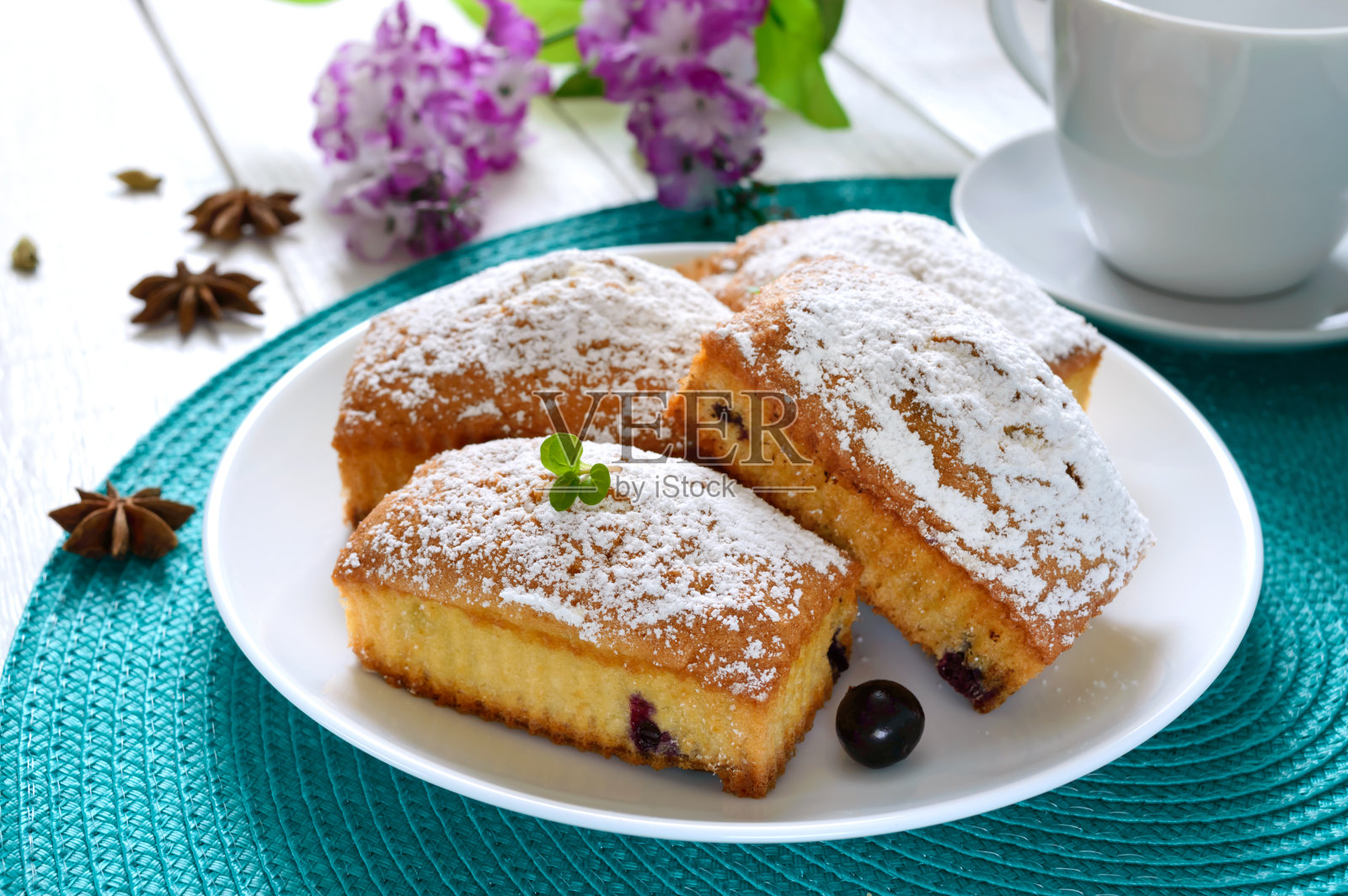 白色木质背景的盘子上放着浆果和糖霜的纸杯蛋糕。长方形的松饼和茶照片摄影图片