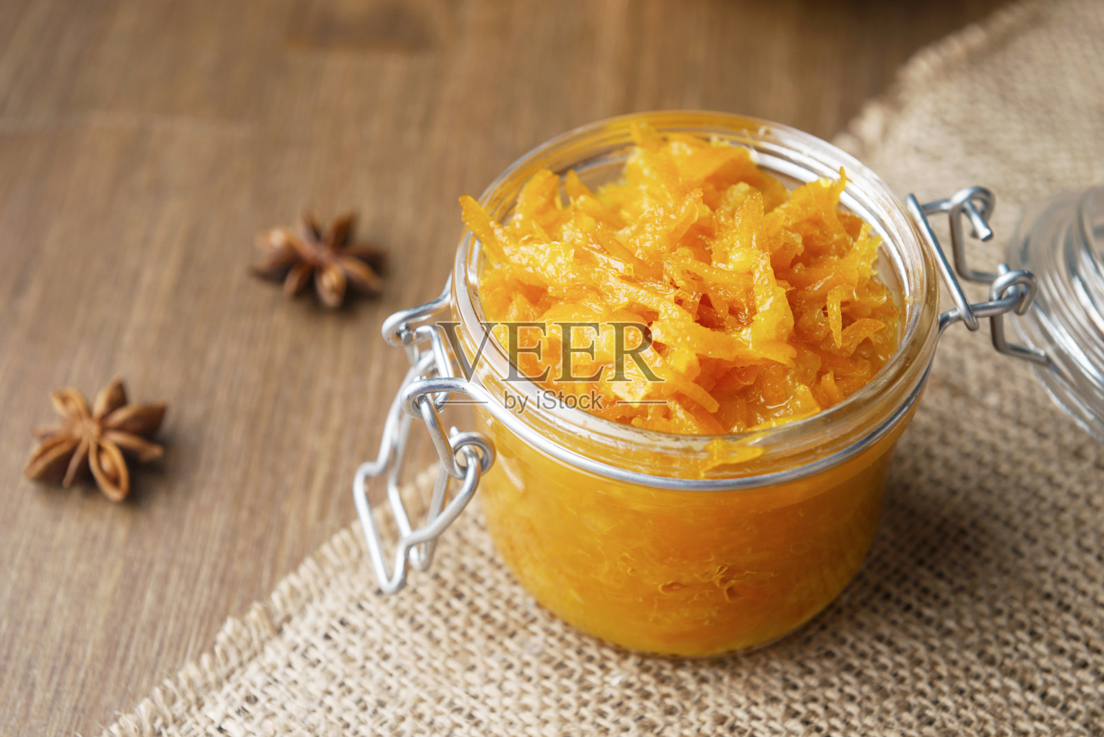 一罐橙色的装饰物，用粗麻布和木制的背景装饰着八角照片摄影图片