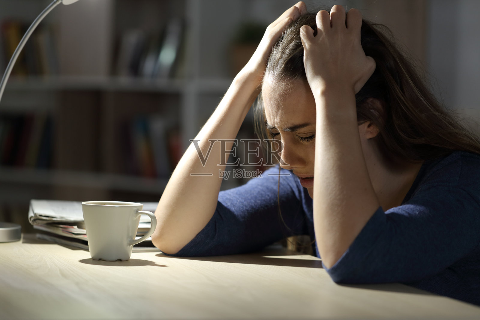 悲伤的女人晚上坐在家里抱怨照片摄影图片