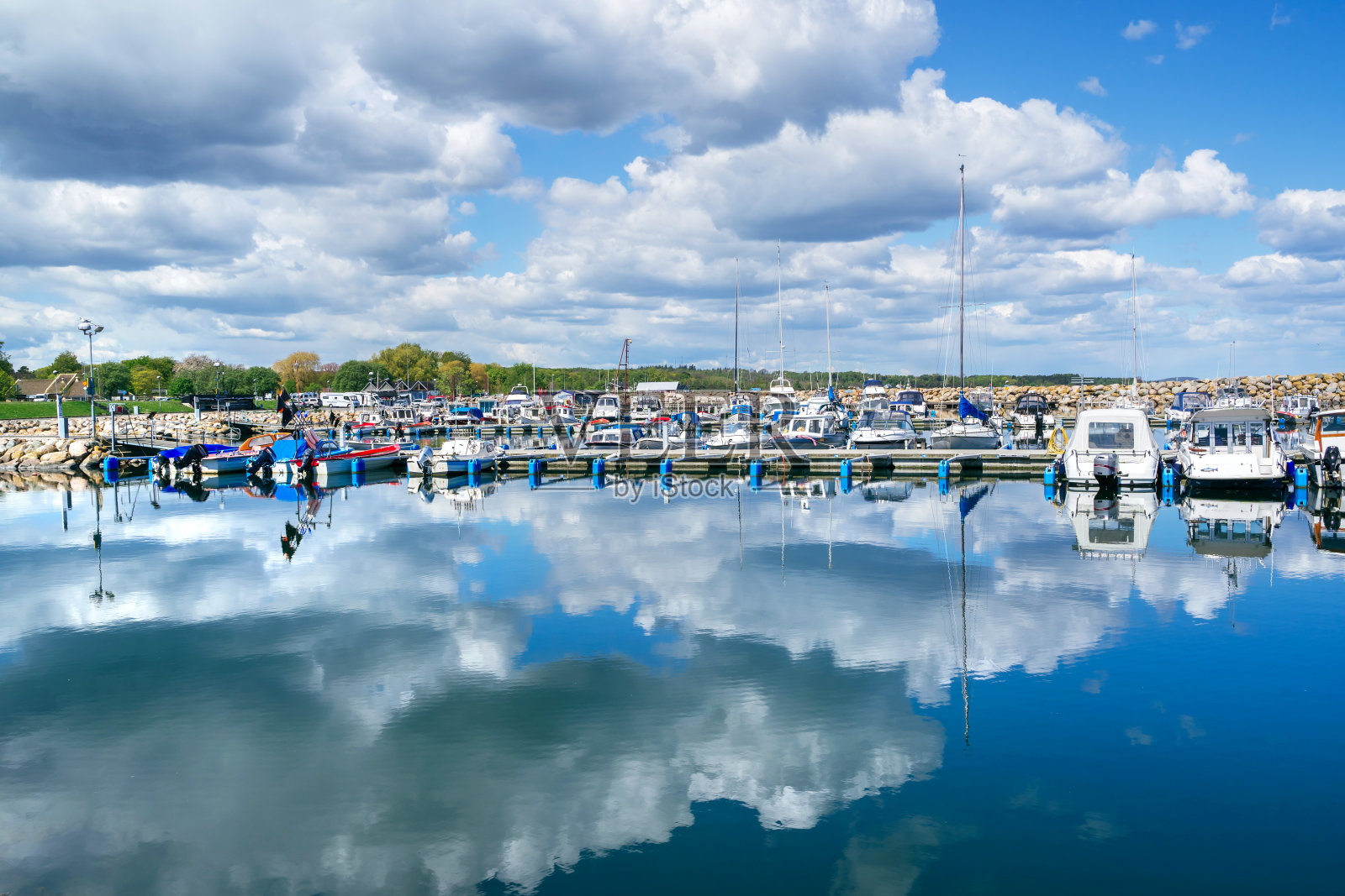2019年5月13日，瑞典西姆里沙姆:阳光明媚的日子里，码头上的小船在水面上倒影照片摄影图片