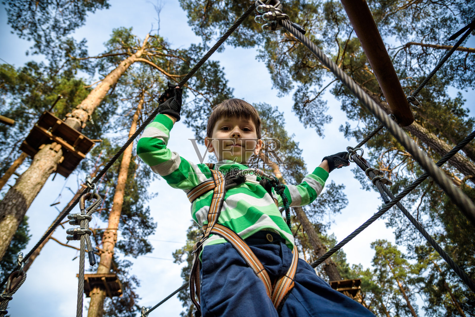 男孩爬上了一个高空铁丝公园。zipline。滑索上的男孩。孩子通过了绳索障碍赛照片摄影图片