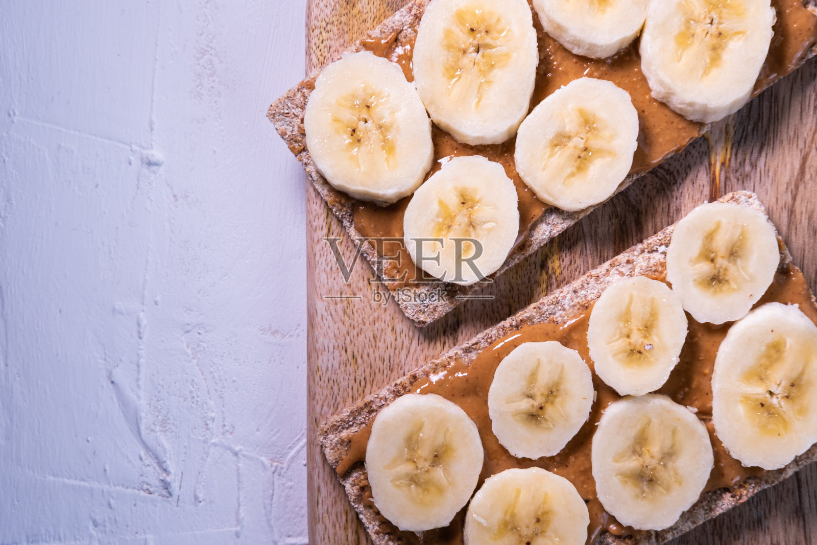 白色背景木桌上的瑞典脆饼配杏仁黄油和香蕉片。健康的零食。前视图。照片摄影图片