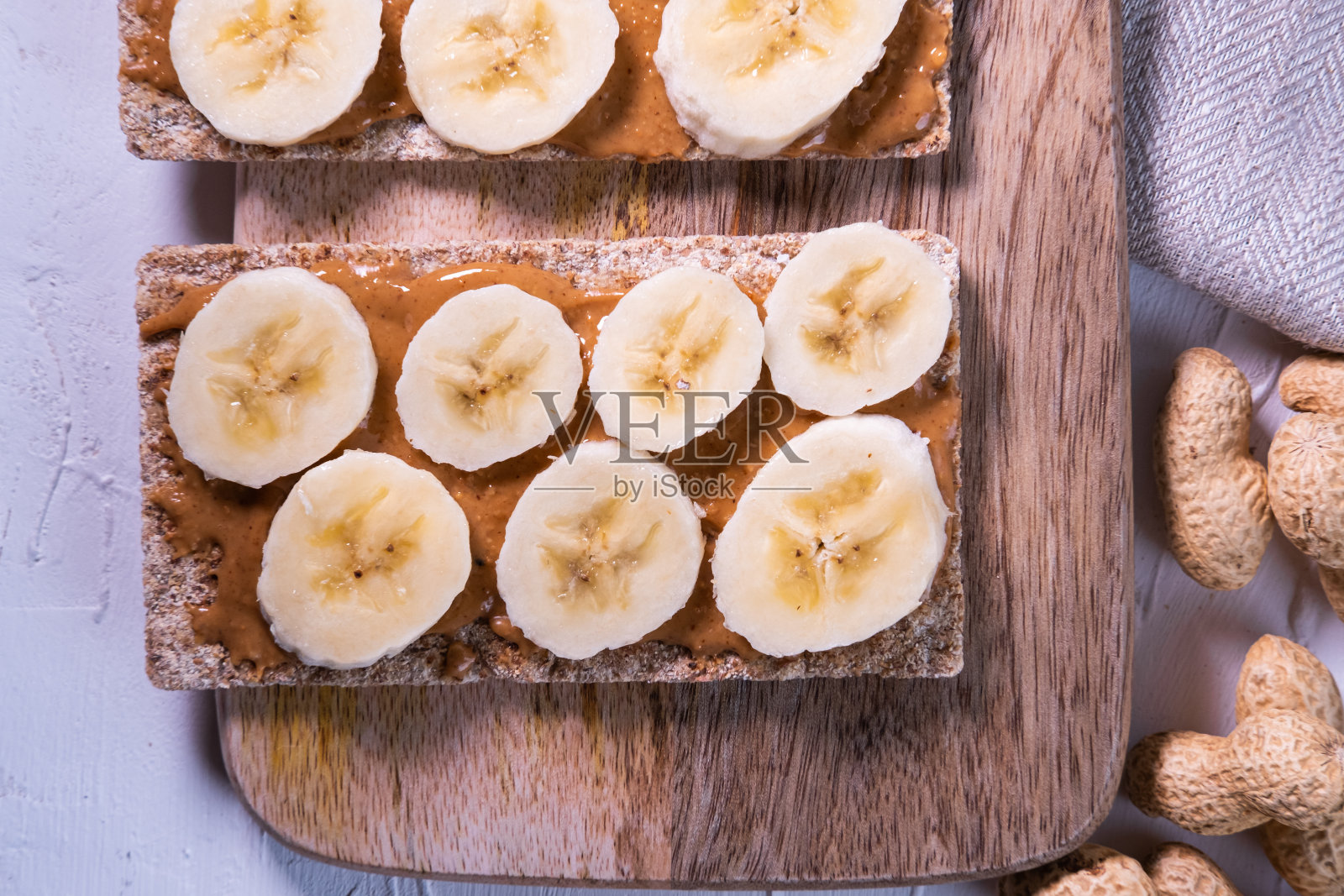 木桌上放着脆饼、花生酱和香蕉。斯堪的纳维亚的零食。健康的生活。前视图。照片摄影图片