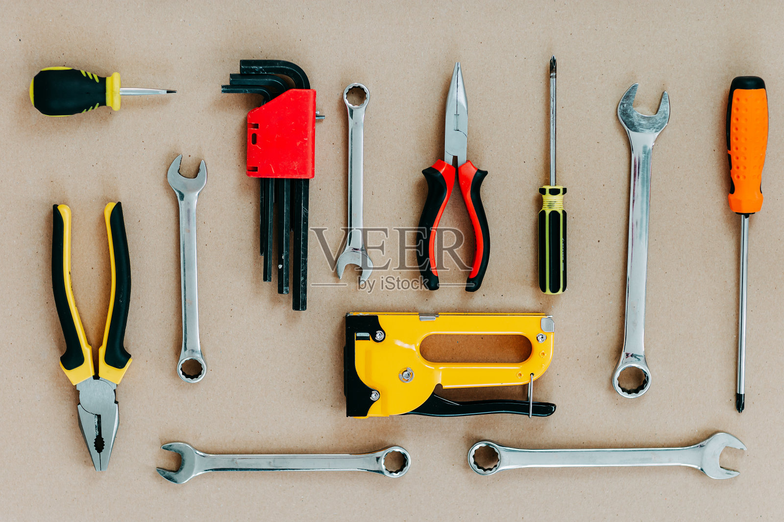 工具在牛皮纸上俯视图。平铺钳，开口扳手，螺丝刀和钉书钉枪。照片摄影图片