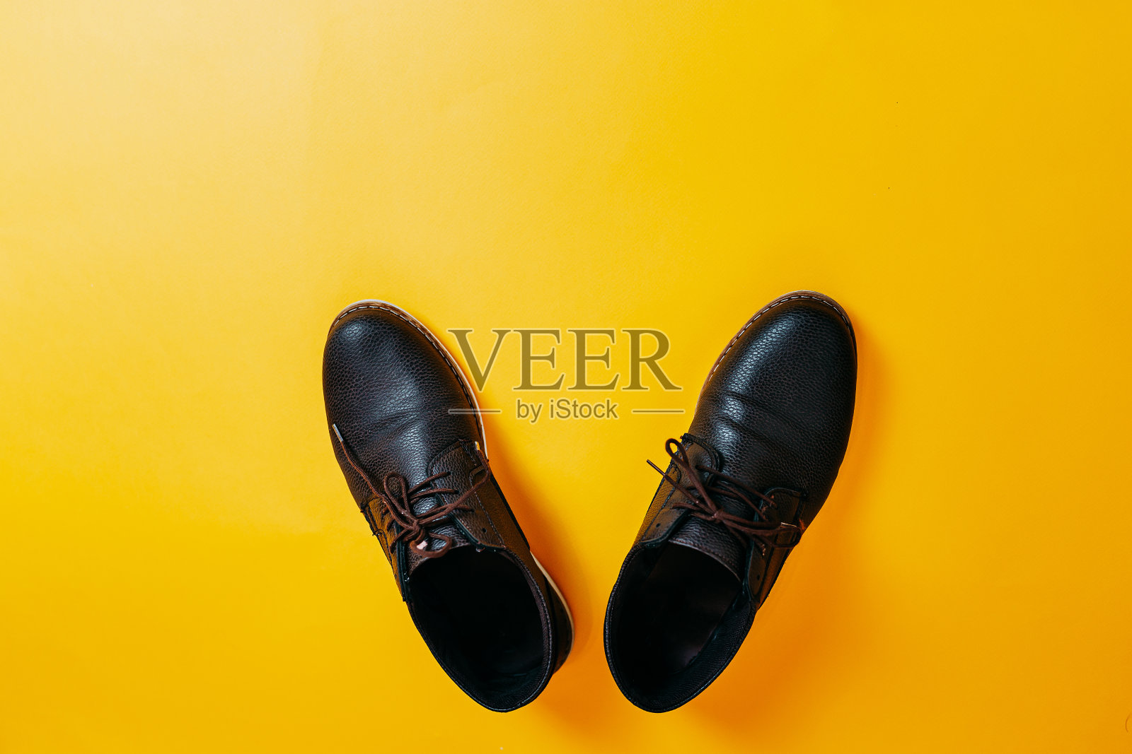 橙色背景上的棕色皮鞋。时尚的皮鞋上的黄色背景。照片摄影图片