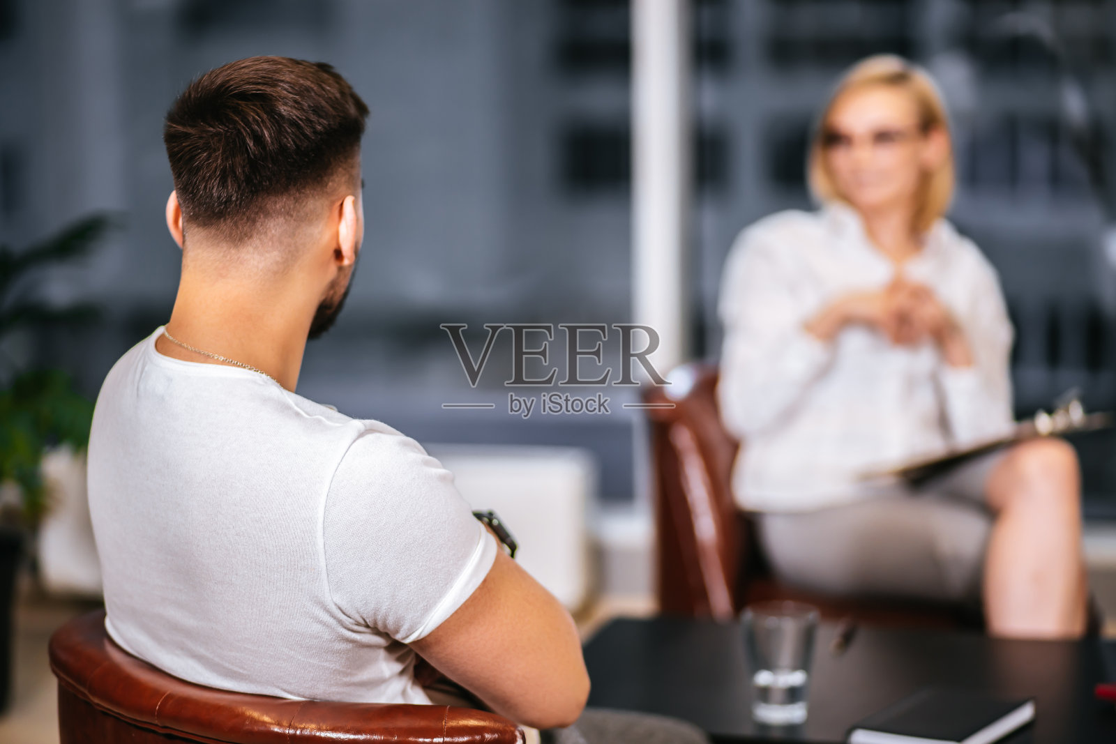 后视图在现代心理学家的办公室治疗年轻男子照片摄影图片