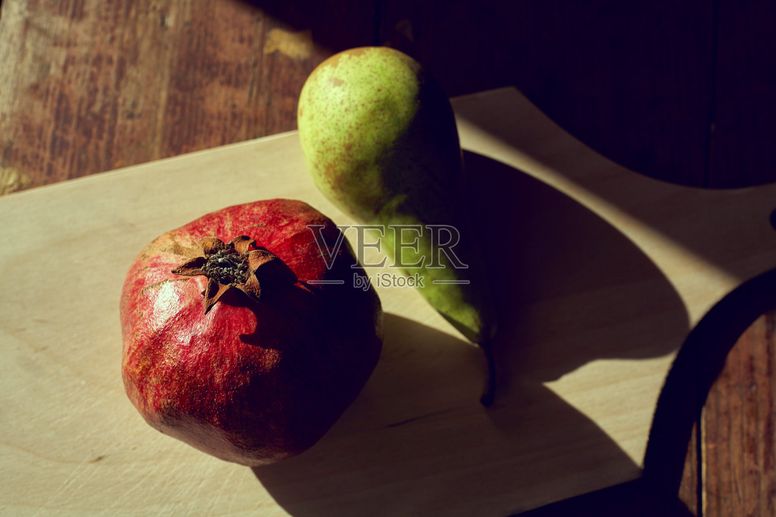 桌上放着石榴和梨子，伴着傍晚的光影和坚硬的阴影照片摄影图片