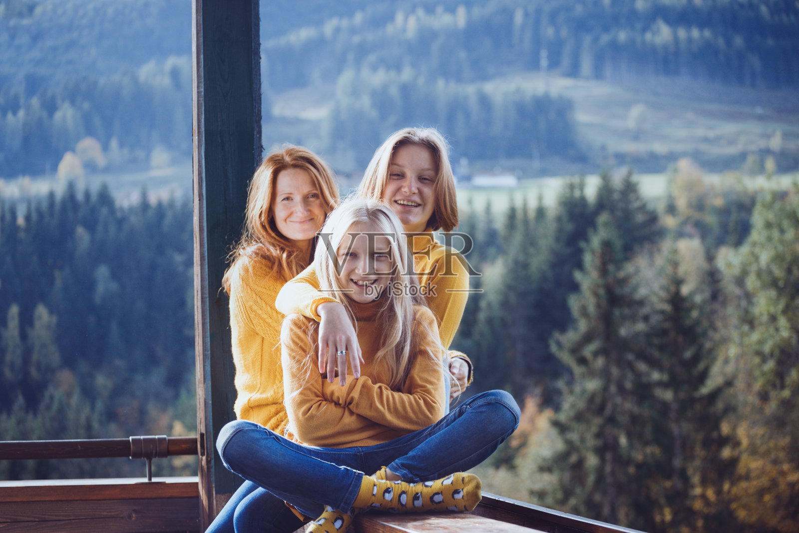 幸福的一家人坐在阳台的栏杆上。清晨，山间小屋照片摄影图片