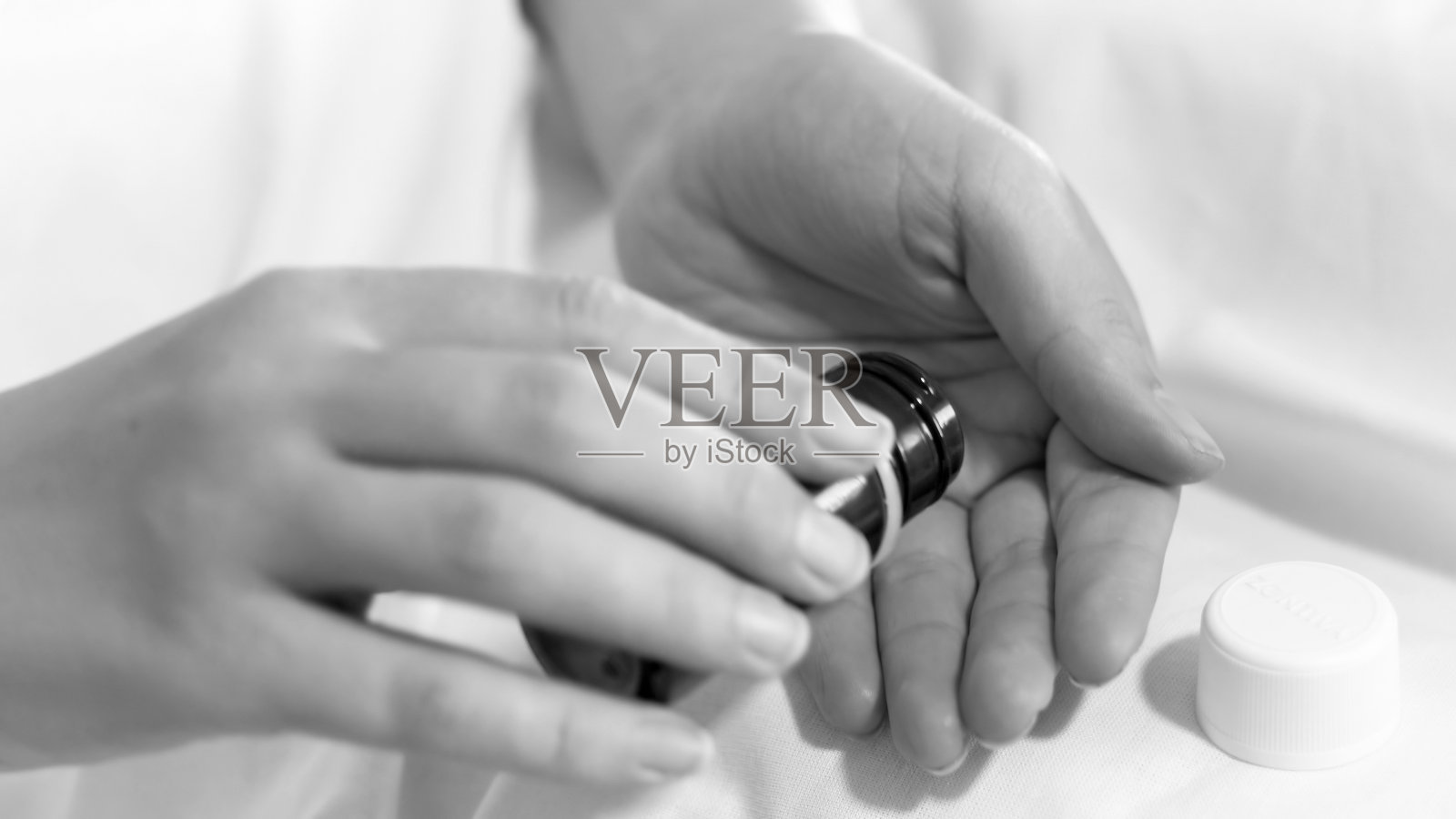 黑色和白色的形象，妇女拿着瓶子和药丸在手里照片摄影图片