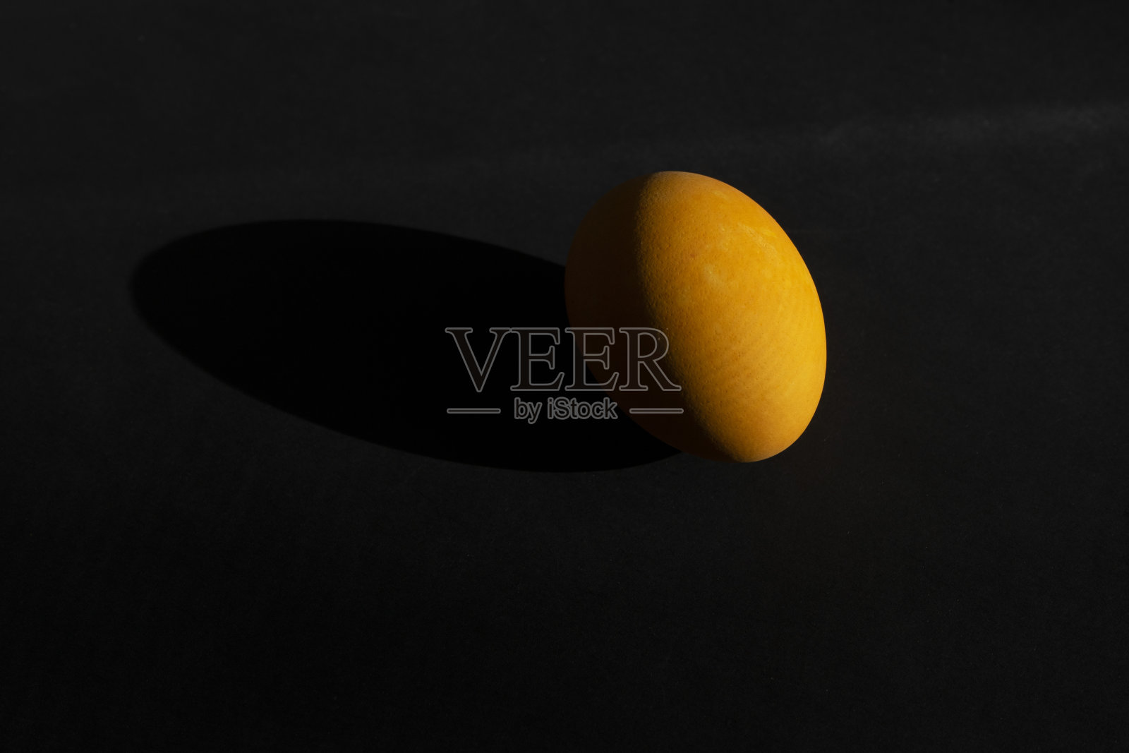 黑色背景上的橙色鸡蛋。宇宙色的鸡蛋，侧光在黑暗的背景上。照片摄影图片