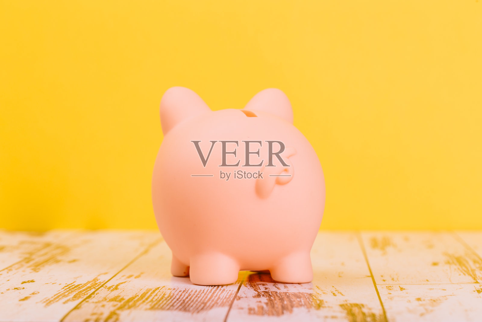 黄色背景上的粉色储蓄罐，文字空间。金融，储蓄，危机。商业或退休储蓄照片摄影图片