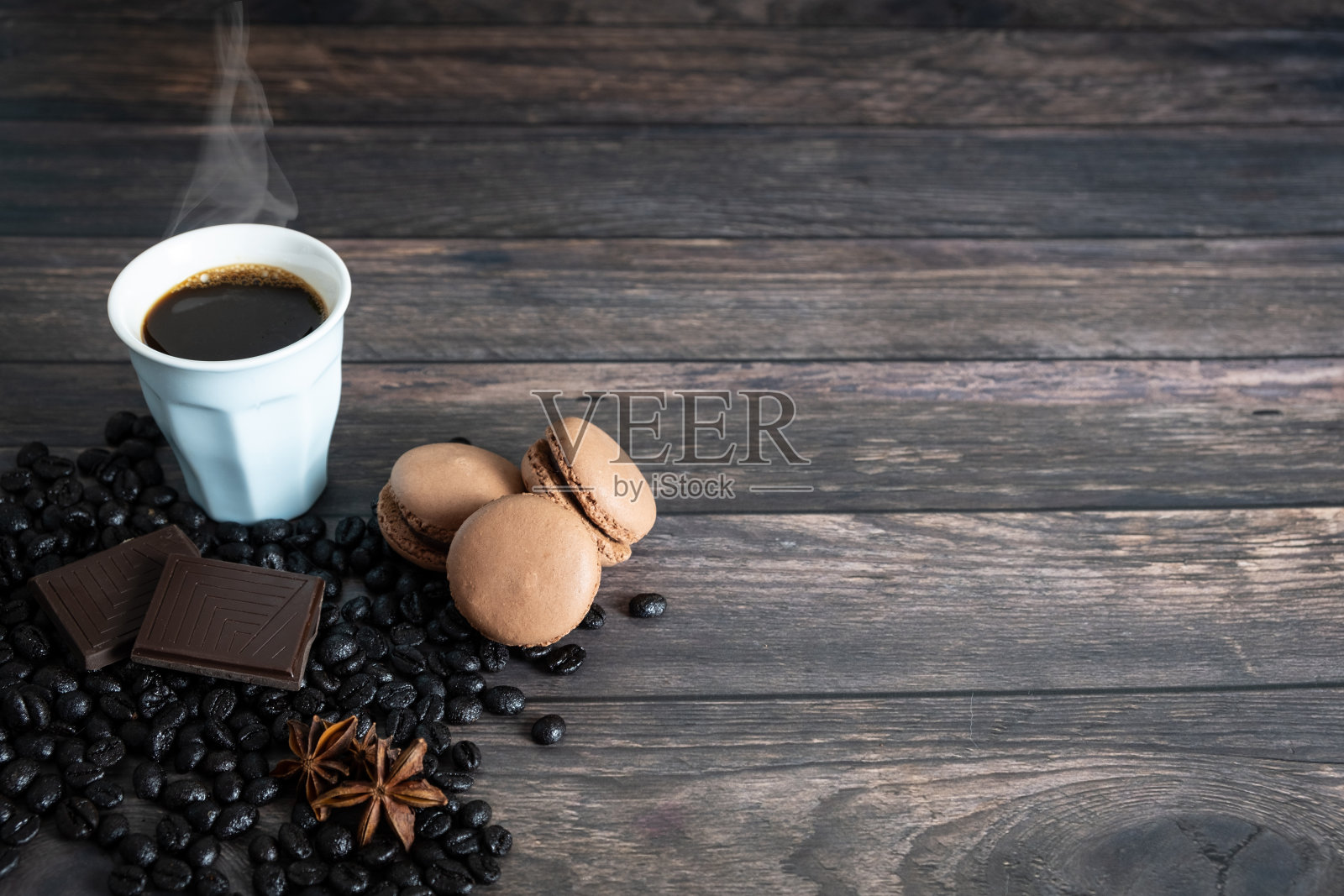 木制背景咖啡杯，咖啡豆，八角，巧克力和咖啡马卡龙。俯视图照片摄影图片