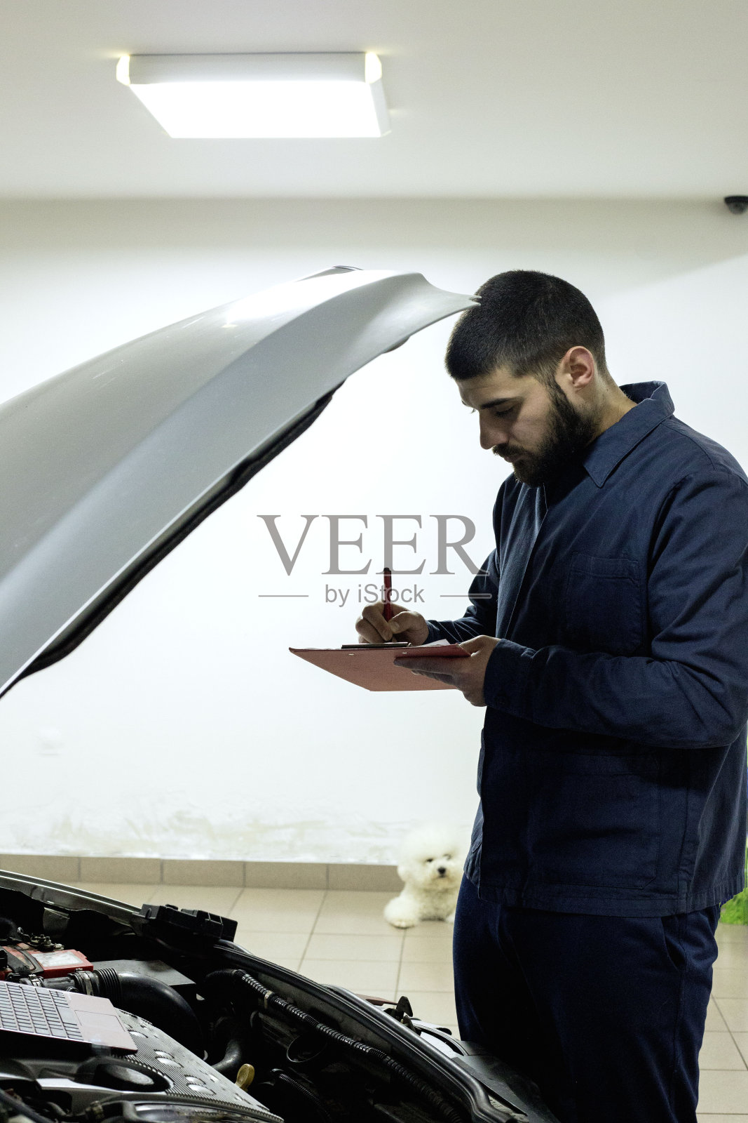 一个年轻英俊的技工在汽车修理厂工作的肖像照片摄影图片