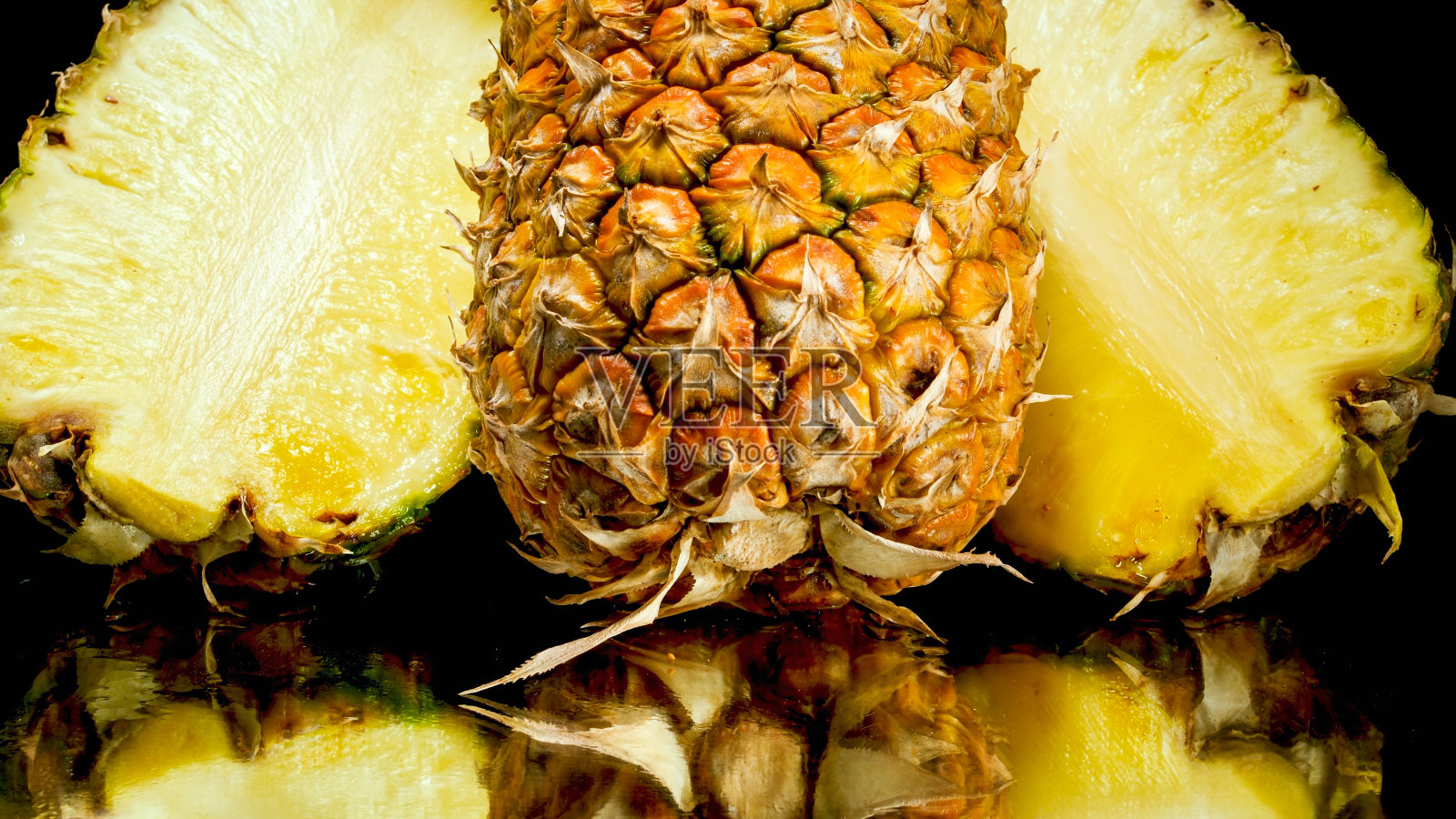 近距离图像切成两半的菠萝躺在黑色的背景上。外来热带水果的摘要背景。照片摄影图片