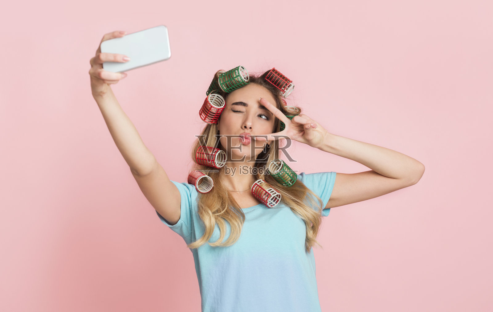 社交网络为家庭主妇的概念。带着卷发器的女孩，在自拍时飞吻照片摄影图片