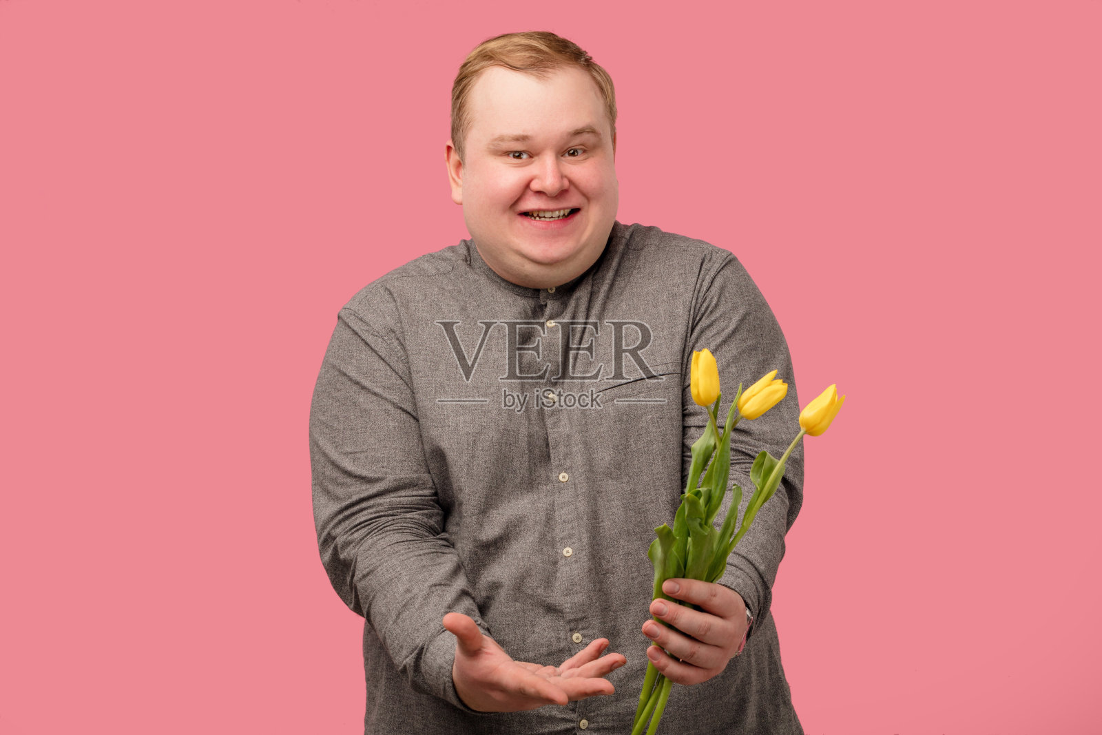 滑稽的男人拿着花准备求婚，他有着开朗的表情和天真的微笑照片摄影图片