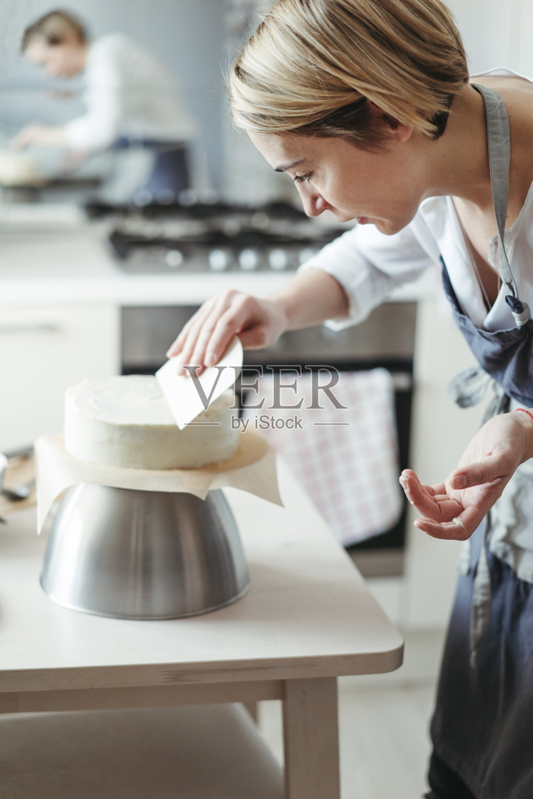 一位中年妇女糕点师或面包师准备蛋糕。照片摄影图片