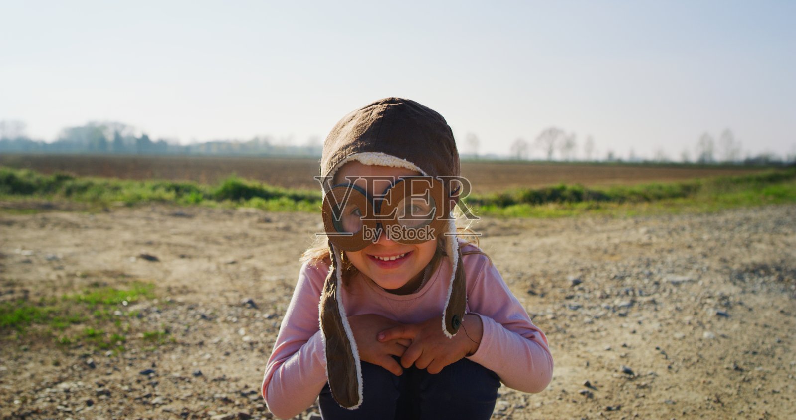 在一个阳光明媚的日子里，一个无忧无虑的小女孩在绿色的自然背景上微笑。照片摄影图片