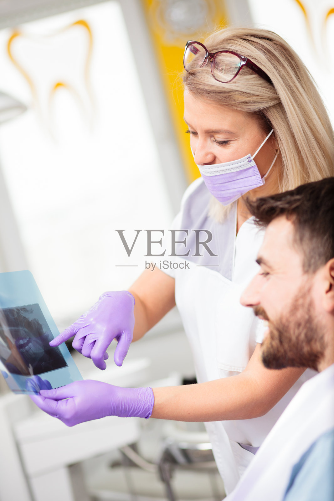 快乐的年轻女牙医向病人展示x光图像照片摄影图片