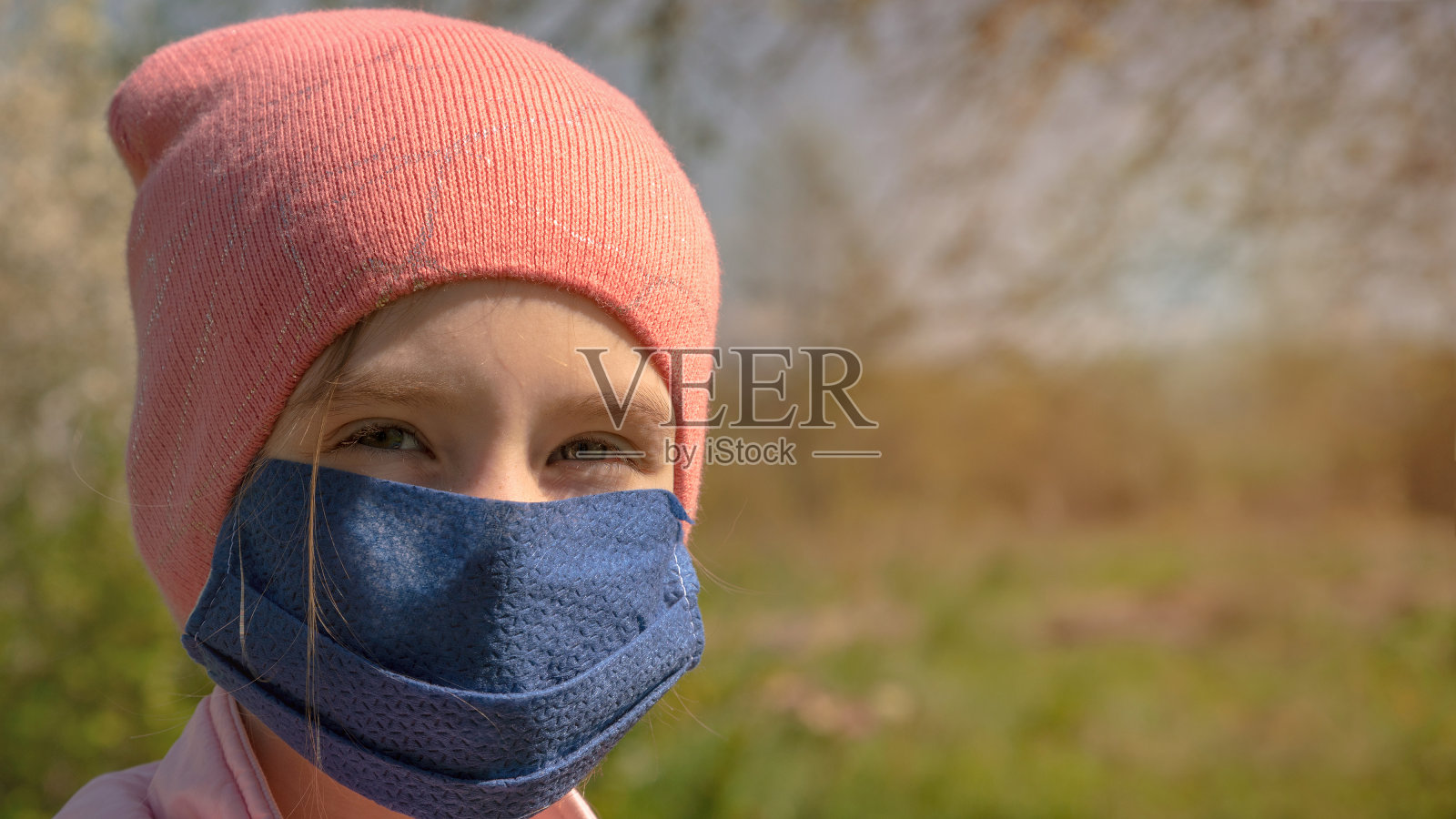 戴着一次性口罩的女孩直视着草地照片摄影图片