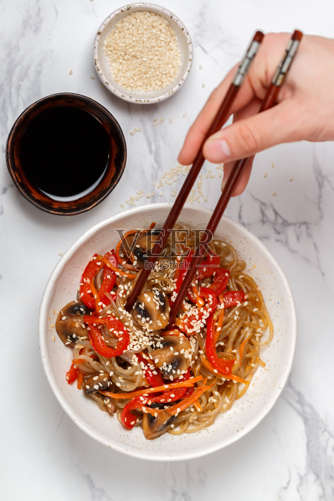 淀粉(米饭，土豆)面条配蘑菇和蔬菜，甜椒，胡萝卜，洋葱，芝麻和酱油。素食菜。美味的晚餐在亚洲(中国，韩国，日本)风格。有选择性的重点照片摄影图片