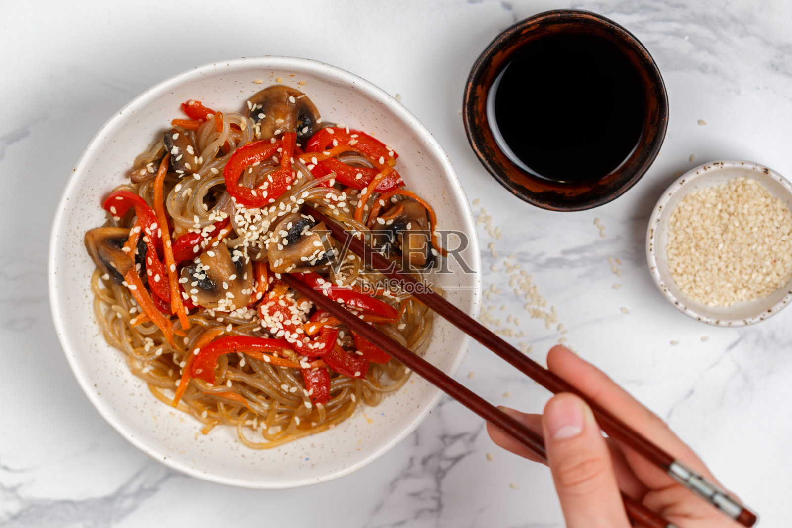 淀粉(米饭，土豆)面条配蘑菇和蔬菜，甜椒，胡萝卜，洋葱，芝麻和酱油。素食菜。美味的晚餐在亚洲(中国，韩国，日本)风格。有选择性的重点照片摄影图片