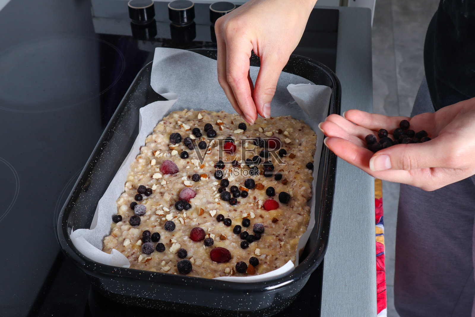 女人在家里厨房用新鲜的浆果手工制作素食披萨。素食的概念照片摄影图片