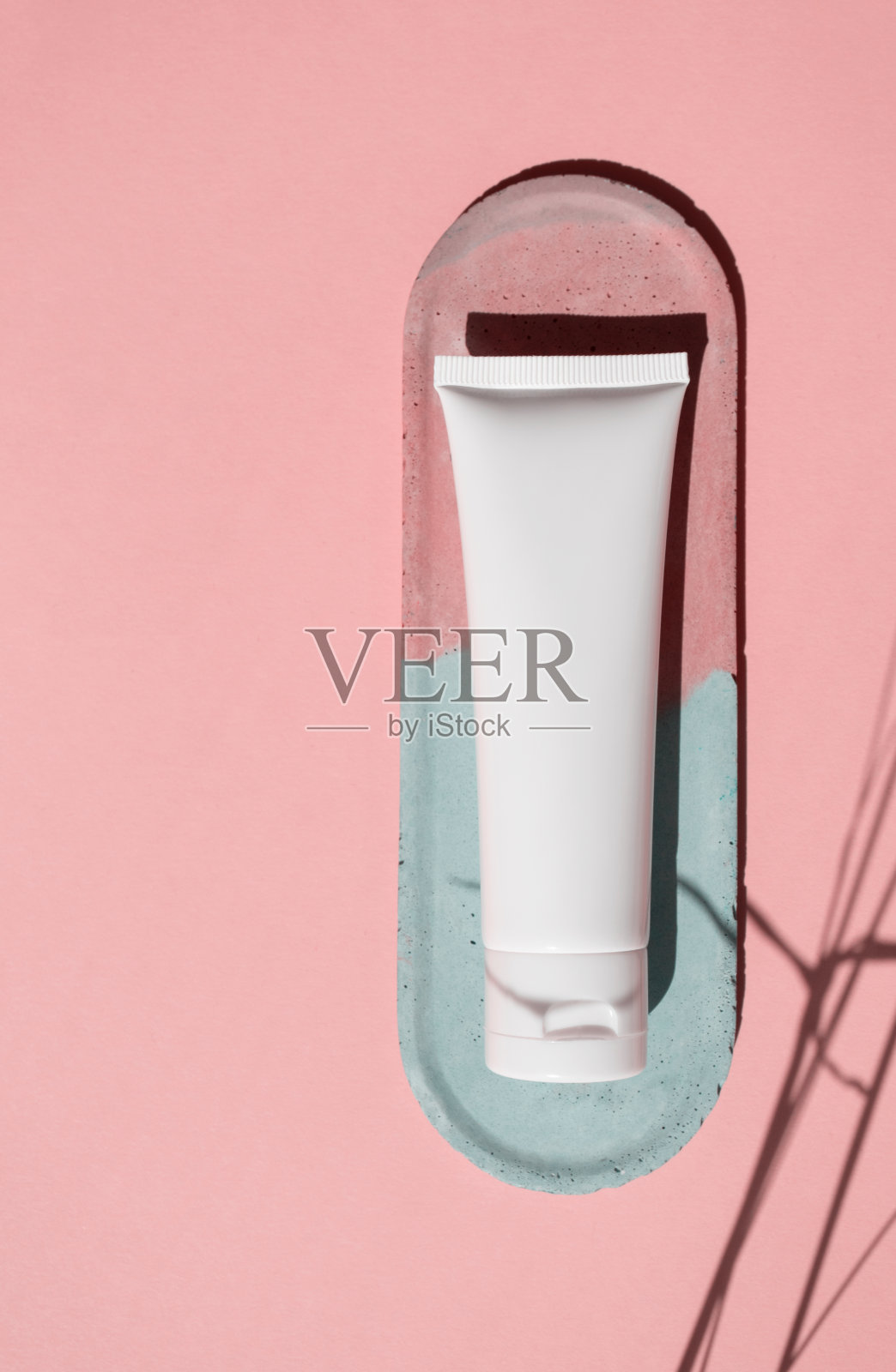 模型白色塑料管化妆品在粉红色的背景与时尚的草本阴影和复制空间，俯视图。装乳霜，保湿霜，乳液，洗面奶的容器放在混凝土装饰板上照片摄影图片