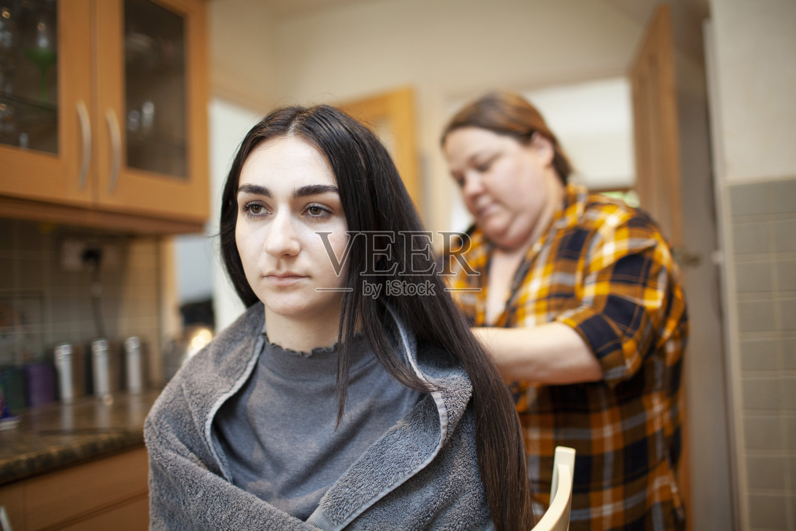 一个年轻女子在家里的厨房里理发照片摄影图片