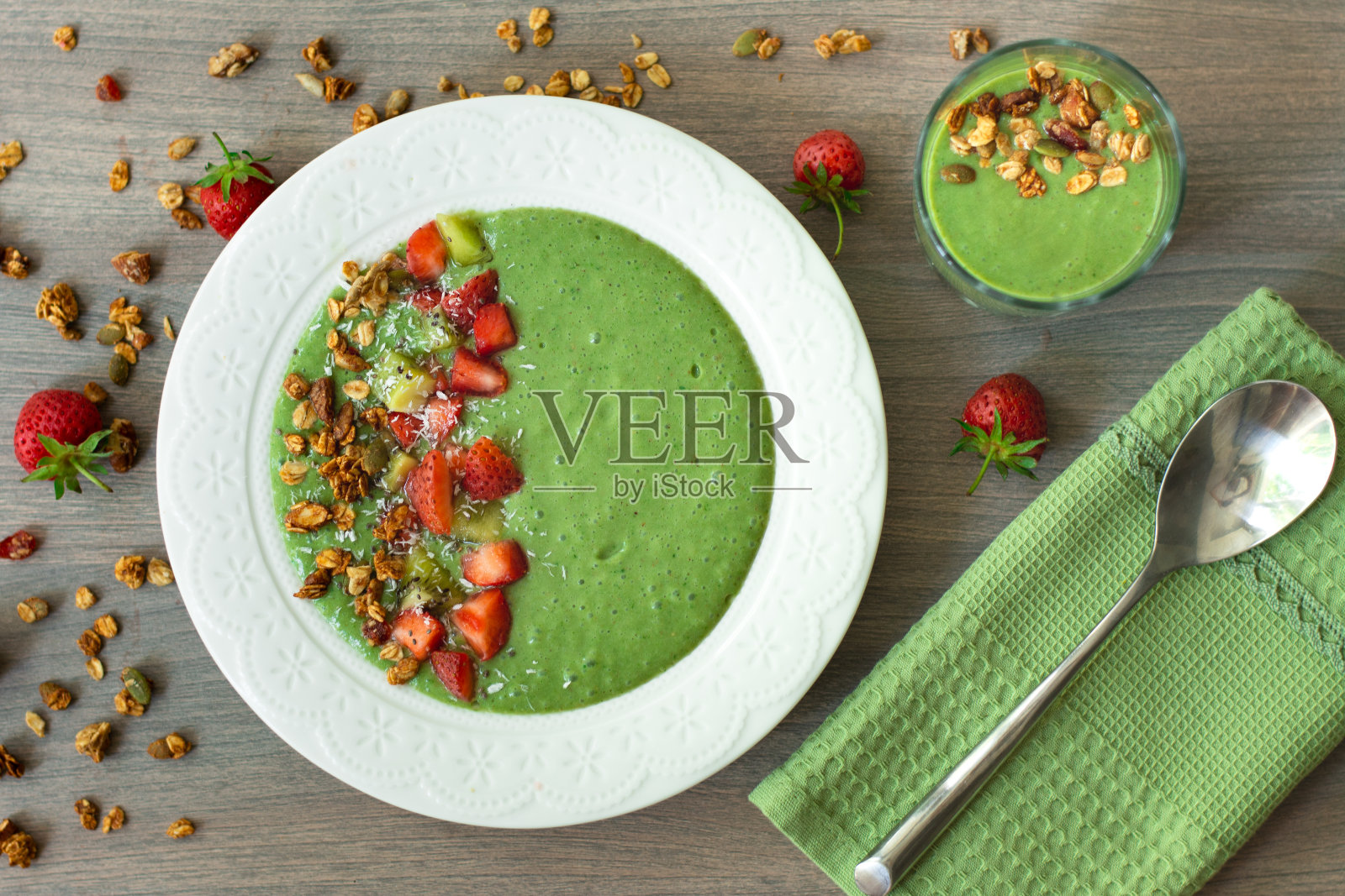 香蕉，草莓，菠菜，甘蓝，猕猴桃，椰奶配自制燕麦，坚果和种子格兰诺拉麦片，椰子片，奇异子，猕猴桃和草莓照片摄影图片