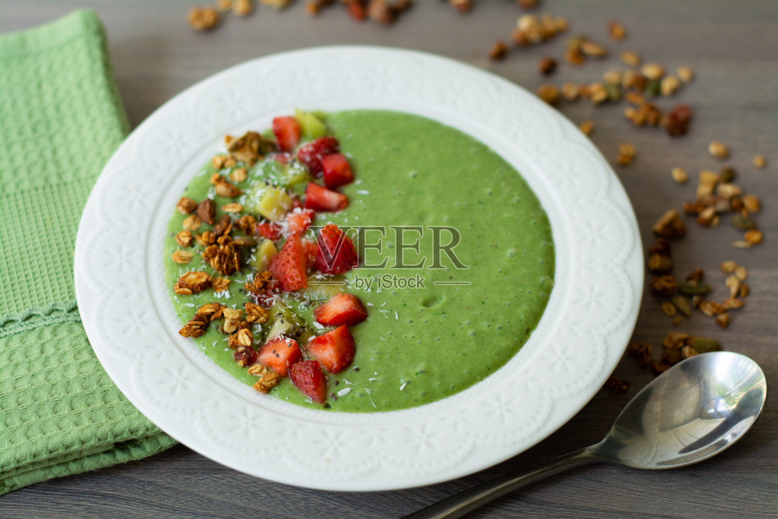 香蕉，草莓，菠菜，甘蓝，猕猴桃，椰奶配自制燕麦，坚果和种子格兰诺拉麦片，椰子片，奇异子，猕猴桃和草莓照片摄影图片